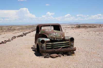 Abandoned car on field against sky