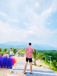 Rear view of man standing on road against sky