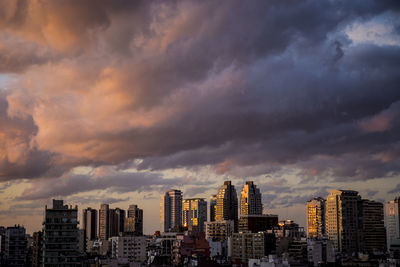 Modern buildings in city against sky during sunset