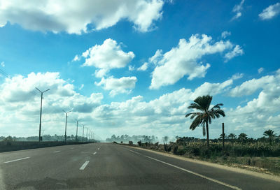 Road by trees against sky