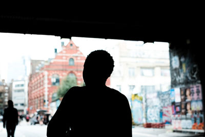 Rear view of silhouette man standing against city