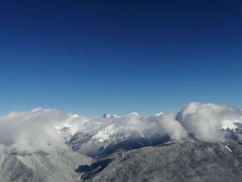 Scenic view of snowcapped mountains against blue sky