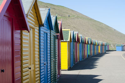 Receding line of colorful wooden beach huts curving away into the distance
