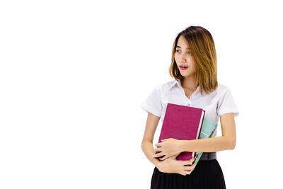 Young woman holding book against white background