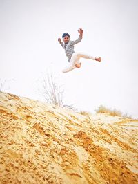 Low angle view of man jumping against sky