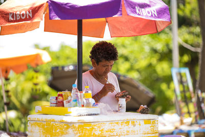 Young woman holding food while sitting on table