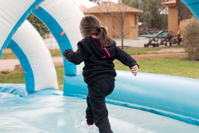 Rear view of girl walking on bouncy castle
