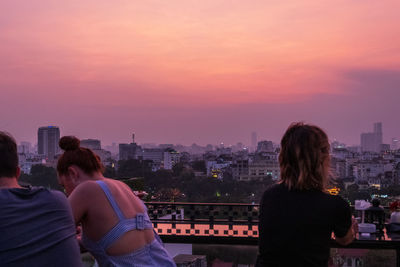 Rear view of people looking at city buildings against sky