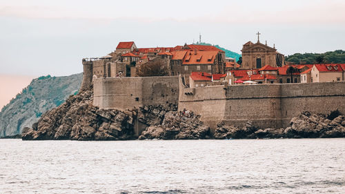 Buildings by sea against sky