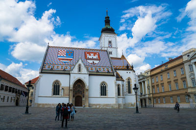 Friend photographing women standing in front of st mark church against sky