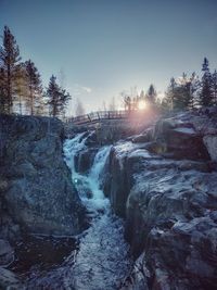 Scenic view of waterfall against sky during sunset