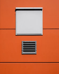 Low angle view of window on orange wall