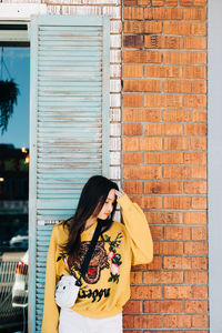 Woman standing against brick wall