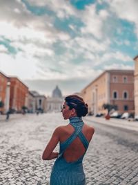 Woman standing on street against buildings in city