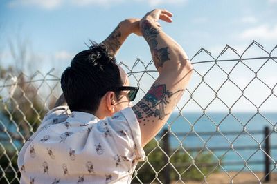 Young man looking through chainlink fence