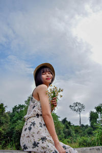 Low angle view of woman standing against trees