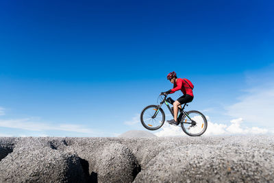 Man riding bicycle against blue sky