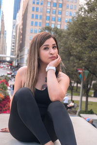 Portrait of beautiful woman sitting in city