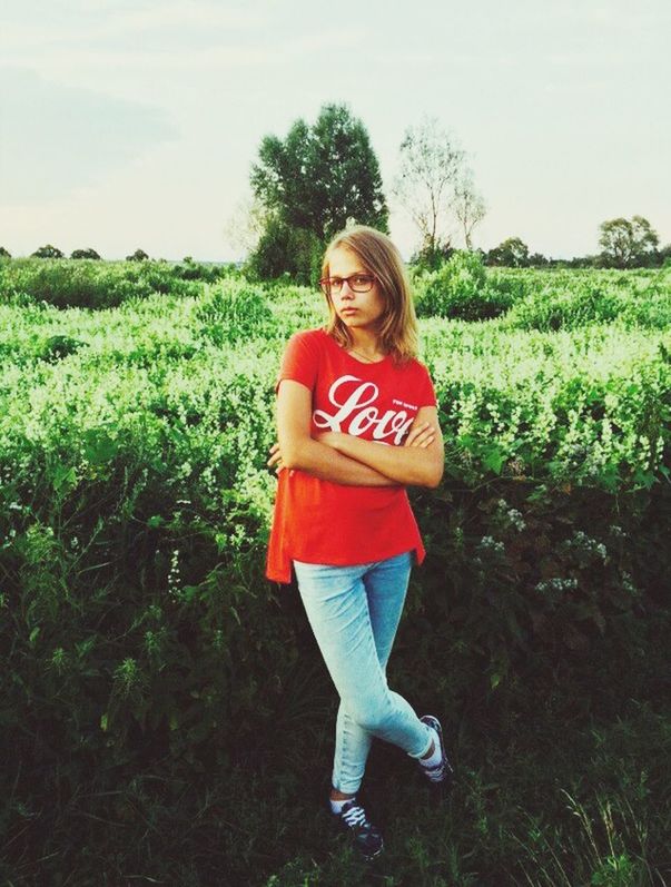 person, young adult, casual clothing, lifestyles, full length, grass, young women, standing, looking at camera, portrait, leisure activity, front view, field, smiling, three quarter length, growth, happiness, plant