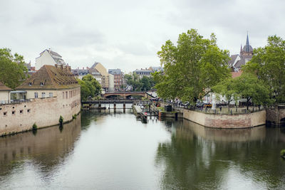 Bridge over river by buildings against sky