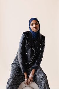 Portrait of young woman sitting against wall