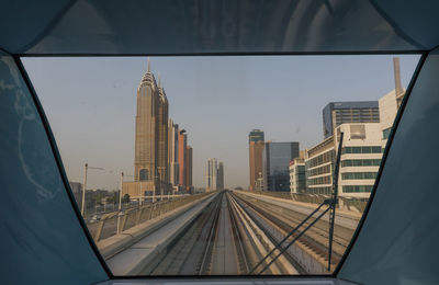 Railroad tracks amidst buildings in city against sky