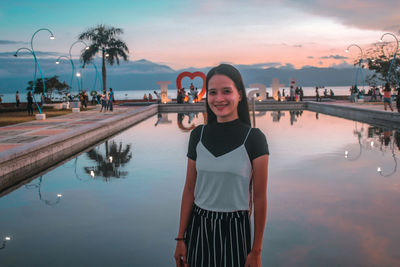 Portrait of young woman standing against sky