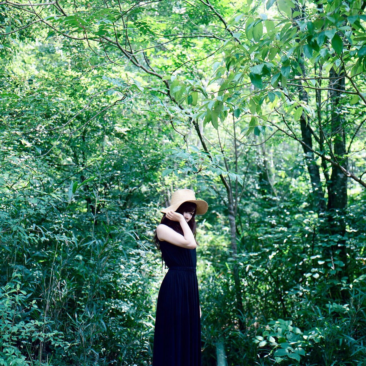 LOW ANGLE VIEW OF A WOMAN STANDING AGAINST TREE