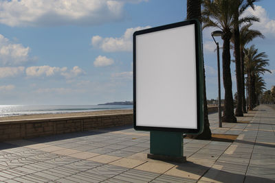 Blank billboard mock up in a sidewalk, next to the sea