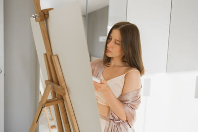 Portrait of young woman standing against wall