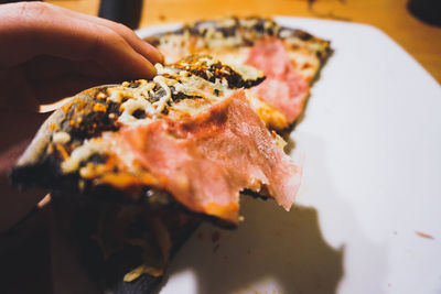 Close-up of hand holding pizza on table