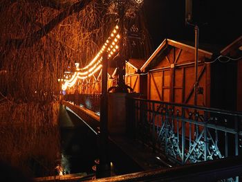 Illuminated footbridge over river at night