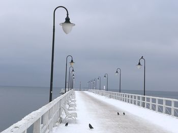 Street light by sea against sky during winter