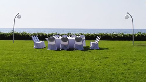 Deck chairs on grass against clear sky