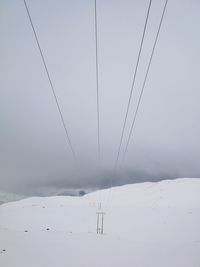 Ski lift over snow covered mountains against sky