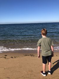 Rear view of boy looking at sea against sky