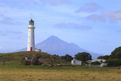 Lighthouse on landscape against sky