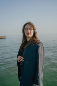 Portrait of young woman standing against sea