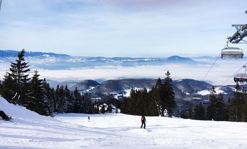 People skiing on snow covered mountain against sky