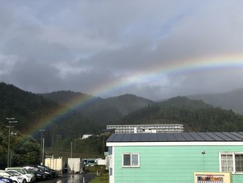 Rainbow over buildings and mountains against sky