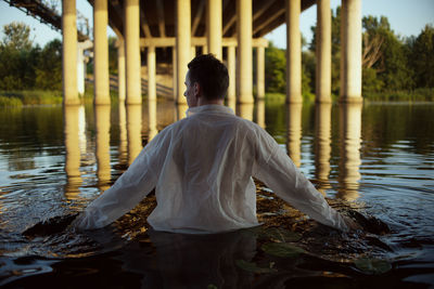 Rear view of man standing by lake