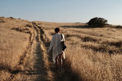 Rear view of woman walking on field