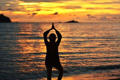 Silhouette man standing by sea against sky during sunset