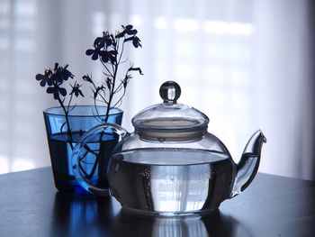 Close-up of teapot by vase on table at home