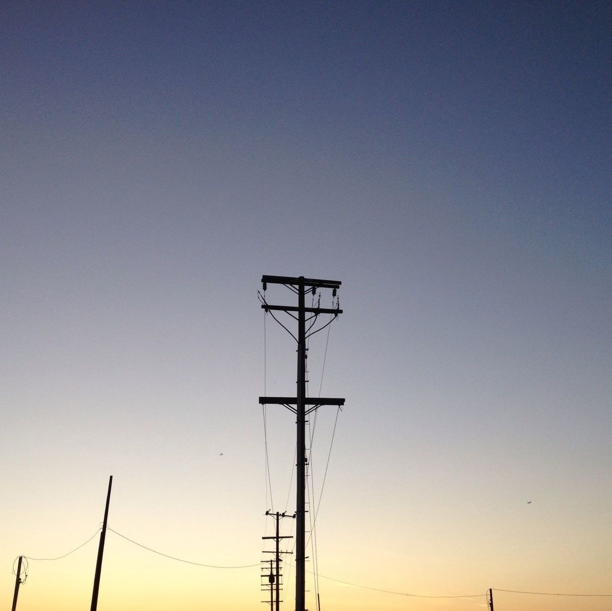 clear sky, copy space, low angle view, technology, electricity pylon, electricity, fuel and power generation, silhouette, connection, power line, sunset, power supply, blue, nature, outdoors, tranquility, no people, sky, beauty in nature, dusk