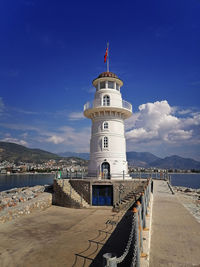 Lighthouse by sea against sky