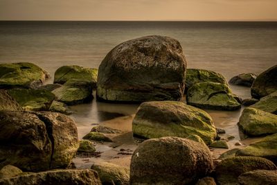 Rocks at sea shore against sky