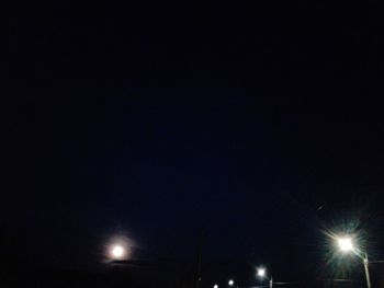 Low angle view of illuminated street lights against sky at night