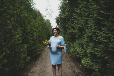 Full length portrait of young man standing against trees