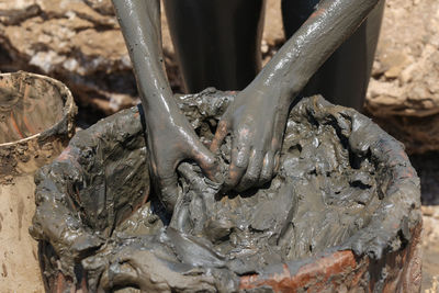 Hands taking dead sea mud from a bucket at the beach, jordan